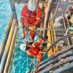 Pekerja konstruksi menggunakan Alat Pelindung Diri (APD) lengkap saat bekerja di atas perancah scaffolding.