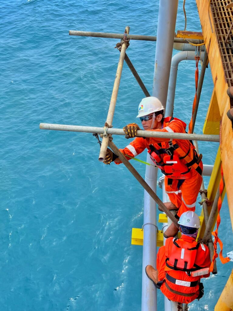 Tenaga kerja scaffolder profesional bersertifikat K3 sedang bekerja.